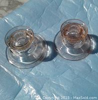 Photo showing two pink depression glass candle holders viewed from above on light blue background.