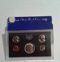 Full view of 1970 USA proof coin set in hard plastic case with blue cardboard backing. Shows all 5 coins arranged on black foam insert.