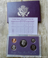 Front view of 1990 USA Proof Coin Set in hard plastic case showing all five coins and specifications chart on purple cover.