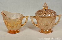 Photo of marigold depression glass creamer showing detailed pattern, handle, and open spout.