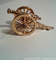 Side profile of one metal desktop cannon piece showing detailed spoked wheels and barrel.