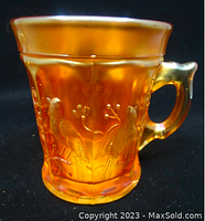 Side view of Northwood Singing Birds Carnival Glass mug showing embossed bird design and textured glass.