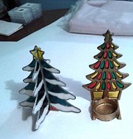 Two metal Christmas tree candle holders; one painted in festive colors, the other silver with white accents.