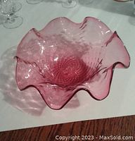 Top and side view of cranberry colored glass bowl showing wavy rim and diamond pattern interior.