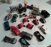Top-down view of 20+ toy cars including Angry Birds character cars, fire engine, sports cars, and vintage trucks laid out on a white surface.