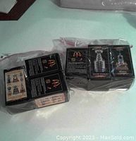 Photo of two packs of McDonalds NHL collectible trophies, Stanley Cup and Vezina Trophy, still sealed in plastic packaging.