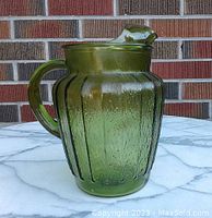 Front and side view of the avocado green ribbed glass pitcher with ice cube lip, showing handle and overall shape