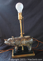 Full view of ceramic rhinoceros lamp with bulb installed and brass pull chain socket on black base.