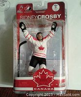 Front view of Sidney Crosby figurine in original packaging showing figure in Team Canada uniform with hockey stick included.