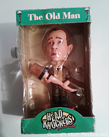 Front view of bobblehead figure inside original packaging showing the figure holding the leg lamp.