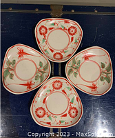 Top view of the set of four vintage dessert plates arranged with floral designs visible, showing red flowers and green leaf patterns on white background.