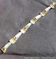 Full view of the vintage silver bracelet laid out straight on dark fabric, showing all linked trapezoidal segments each with a stone inlay.