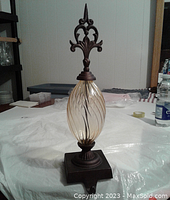 Full vertical view of vintage decorative stocking hook showing glass body and metal finial top