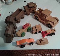 Photo of the full wooden toy collection showing the train engine, train cars, car truck, small cars, boat, and tractor.