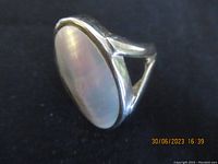 Close-up image showing the oval mother of pearl centerpiece mounted in a sterling silver setting with polished finish and split band design.