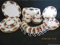Full set of Royal Albert Old Country Roses china including plates, cups, saucers, serving platters, and salt and pepper shakers, arranged neatly on black backdrop.
