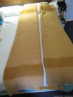 Two folded wool blankets laid side by side on a bed, showing overall length and pattern.