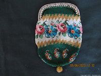 Top view of small coin purse showing bright floral glass beadwork on green background and metal frame with decorative edge.