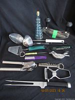 Full view of assorted vintage kitchen utensils arranged on black fabric background.