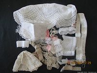 Various antique and vintage lace trims and fabric pieces laid out on black background, showing different patterns and textures