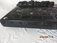 Close-up angled side view showing peg holes and carved detail on edge of board.