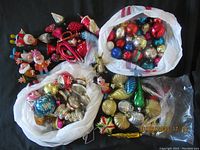 Overview of lot in bags showing a variety of red, blue, gold, and silver vintage Christmas ball ornaments with character figurines scattered around.