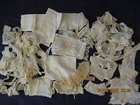 Various vintage lace pieces laid out on a dark surface, showing a mix of crochet and openwork lace in cream and off-white colors.