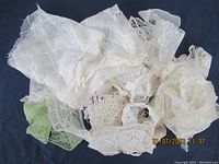 Pile of assorted white and off-white vintage lace trims showing various patterns and textures