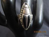 Front view of vintage silver stag beetle ring showing beetle design with black enamel and marcasite stone border on a black ring holder.