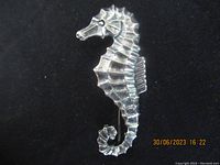 Front full view of sterling silver seahorse brooch against black background showing entire shape and form.