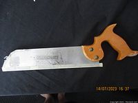 Full view of the vintage Swedish hand saw with wooden handle and curved end saw blade.
