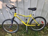 Side view of the full yellow Raleigh Rocky mountain bike showing frame, tires, seat and pedals.
