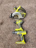 Photo of Ryobi cordless circular saw, impact driver, and drill aligned vertically on carpet showing overall condition.