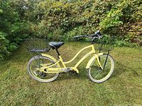 Full side view of the light yellow cruiser bicycle showing frame, wheels, and baskets