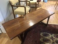 Photo showing the entire teak coffee table with two chairs in the background and Persian rugs beneath.