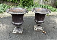 Pair of urns side by side on paved surface, front view