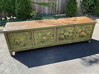 Front view of antique Chinese low cupboard showing green painted panels with floral decorations and wood top surface.