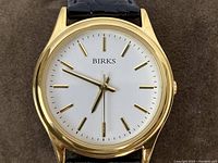 Close-up of watch face showing BIRKS logo, white dial, gilt markers and hands