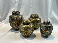 Four urns grouped on white drape, no scale reference