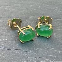 Front view of gold peridot stud earrings on flat surface