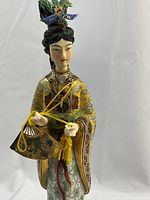 Close-up photo of the enamel cloisonne figurine showing detailed facial features, clothing, and hairpiece.