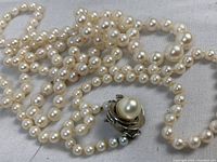 Close-up view of pearl beads and silver clasp with attached pearl