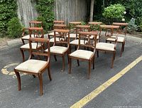 Group view of all 12 mahogany Regency style chairs outdoors on asphalt