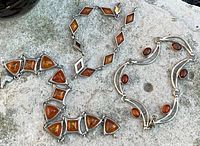 Overview of all three amber and sterling silver bracelets on stone background