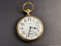 Front view showing white porcelain dial with black Arabic numerals and blue steel hands