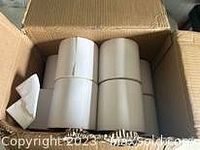 Box containing 10 large rolls of blank white labels viewed from above, showing the rolls neatly arranged inside a cardboard box.