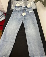 Three pairs of Maurices jeans laid out with tags visible, showing they are new and size 14W.