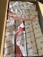 Box containing 8 packages of Hammermill pink printer paper with one package's outer plastic wrapping torn.