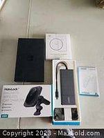 Top-down view of multiple electronic items including a rectangular power bank with cables, a black Haibao wireless car charger, its box, and a small blue pouch.