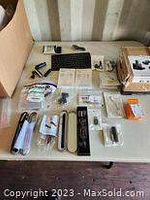 Overall view of all electronic and communication accessories laid out on a table including chargers, cables, adapters, speakers, and gadgets.